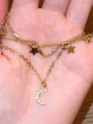 Guldigt halsband med stjärnor och måne - Snyggt lager-på-lager halsband i guldfärgad metall med små stjärnhängen och en måne dekorerad med glittrande stenar. Perfekt för dig som gillar trendiga detaljer och vill ha något unikt till din outfit. Justerbar längd och tunn kedja.🥹🧸🩷