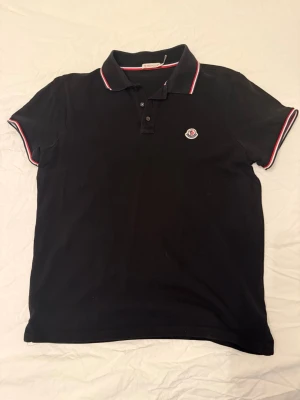 Svart Moncler piké - Moncler piké i storlek S, väldigt bra skick, bild på koden som visar länk! Pris kan diskuteras vid snabb affär!