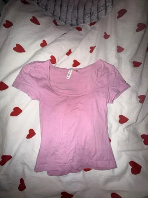 Ljusrosa croptop - Söt ljusrosa babytee från HM med rundad, djup urringning och korta ärmar. Enkel och clean design som passar till det mesta.🩷🩷använd 1 gång då jag inte är ett fan av rosa 