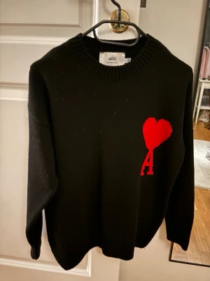 Ami Paris - S o l d e n svart stickad tröja från Ami Paris med röd hjärtlogga och bokstaven A serious på bröstet. För liten för mig💓 pris kan diskuteras vid snabb affär