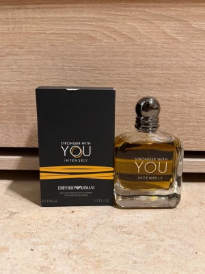 Emporio Armani Stronger With You Intensely - Emporio Armani Stronger With You Intensely är en parfym för honom med en elegant, fyrkantig glasflaska och silverfärgad rund kork. Doften kommer i en svart kartong med orange detaljer och har en varm bärnstensfärgad vätska. Flaskan rymmer 100 ml och utstrålar lyxig och modern känsla.
