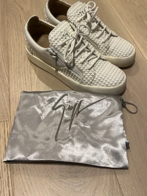 Vita sneakers från Giuseppe Zanotti - Säljer nu ett riktigt unika par vita Giuseppe zanotti skor i väldigt bra skick, skorna kostar cirka 8000 kr ny pris men jag säljer de för betydligt mycket billigare. Du får med dig dustbag. Tveka inte på att höra av er😁 Priset är ej hugget i sten!
