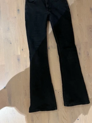 Svarta low waist bootcut jeans - Säljer ett par svarta bootcut jeans med utsvängda ben. Jeansen har låg midja och är tillverkade i ett mjukt denimtyg som sitter snyggt. 