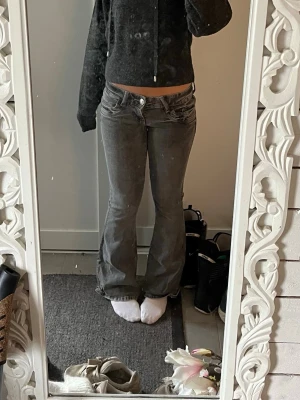 Grå bootcut jeans med låg midja - Säljer ett par grå bootcut jeans med låg midja. Jeansen har en lätt utsvängd passform nertill och stängs med knapp och dragkedja. Perfekta för en avslappnad och trendig look. Knappt andvönda, jättebra skick! Pris kan diskuteras🥰🫰🏼🫰🏼