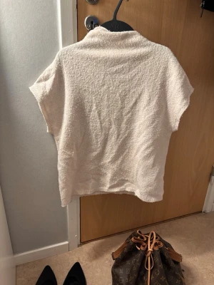 Krämvit stickad topp från Lindex - Säljer en krämvit stickad topp från Lindex med korta ärmar och lös passform. Materialet är mjukt och har en lätt struktur, perfekt för lager på lager eller som den är. Enkel och stilren design som passar till det mesta.🤍