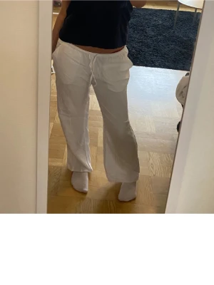 Vita linnebyxor med dragsko - Säljer ett par vita linnebyxor från hm med avslappnad passform och resår i midjan med dragsko. Byxorna har raka ben och är Lågmidjade. Materialet är linne vilket gör dem svala och bekväma perfekt till sommaren. Har även ett par i svart!!🥰