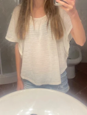 Vit spets t shirt - Säljer en vit, luftig topp med korta ärmar och rund hals. Poncho aktig. Storlek M