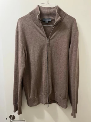 Beige Cashmere ziptröja från Snoot - Stilren beige ziptröja från Snoot med hög krage och ribbade muddar. Tröjan har hel dragkedja framtill och är tillverkad i mjukt stickat material. Perfekt för lager-på-lager och enkel att matcha med olika outfits. Dragkedjan är lite trög ibland men inte något farligt