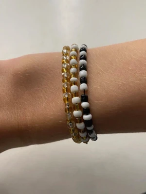 Färgglada pärlarmband i set om tre - Tre armband med små pärlor i olika färger: ett i gult och transparent, ett i svart och vitt samt ett i vitt och svart. Perfekta för att ge din stil en personlig touch. Armbanden är elastiska och passar de flesta handleder. Säljer i fler färger också, ett för 10kr. (Typ) 