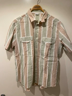 Randig kortärmad skjorta - Kortärmad skjorta med breda vertikala ränder i beige, grön och vit. Passar som M (men lappen står XL). 