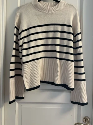 Randig stickad tröja - Beige randig stickad tröja med slits på båda sidorna. Använt någon gång 