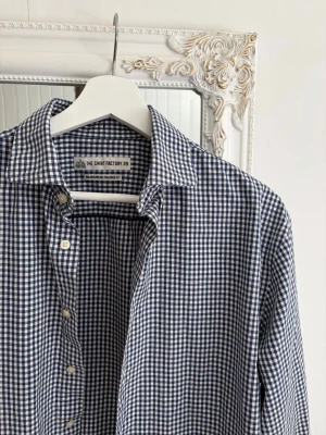 Blåvit rutig skjorta från the Shirt Factory - Säljer en riktigt snygg skjorta från The Shirt Factory. Skjortan är som ny och har inga skador. Storlek 39.
