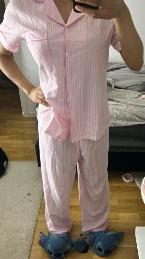 Rosa- och vitrandig pyjamas med kort ärm - Söt pyjamas med kortärmad skjorta och långa byxor i rosa och vita ränder. De är för stora för mig så har inte använt den