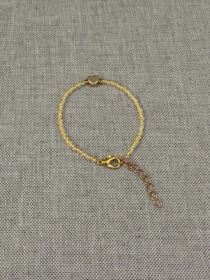 Gult armband med hjärta - Handgjort armband med små ljusgula pärlor och guldfärgade detaljer. Armbandet har ett litet hjärta i metall och justerbar kedja för perfekt passform. 