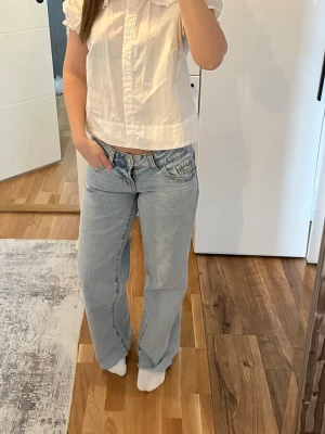Ljusblå raka jeans med låg midja - Säljer ett par ljusblå jeans med rak passform och låg midja. Jeansen har klassiska fem fickor och en avslappnad look, perfekta för en trendig och casual stil. Materialet är denim i bomull och de har en snygg tvättad finish. Jag är 161cm