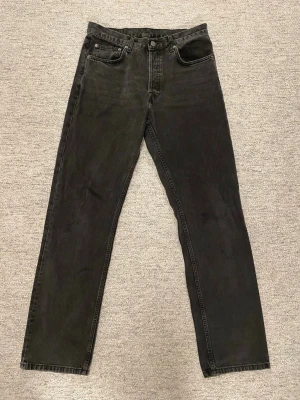 Svarta raka jeans från Dr Denim - Säljer ett par svarta jeans från Dr Denim med rak passform och klassisk femficksdesign. Jeansen har en snygg tvättad look och är tillverkade i denim med tydliga sömmar. Perfekta för dig som gillar stilrena och tidlösa jeans.