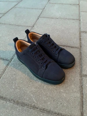 Blåa Christian Louboutin - Snygga mörkblåa Louboutins med klassisk låg profil och mocka material. Skorna har blåa snören och röd sula. Perfekta för dig som gillar stilrena skor. Fraktar inom en dag. Boxen kommer med