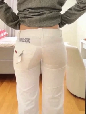 Vita unika jeans vintage lowwaist - Säljer ett par vita jeans från ONLY med raka ben och låg midja. Jeansen har en unik detalj med tryck på linningen och en ficka med lock och band bak. Perfekta för dig som vill sticka ut med en clean och modern look. Midjemått:38 Innerbenslängd: 77