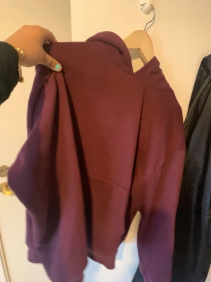 Mörklila hoodie med huva - En oversized mörklila hoodie med huva och långa ärmar. Hoodien har en klassisk, enkel design utan synliga tryck eller loggor. Perfekt för en chill och avslappnad stil. Materialet ser ut att vara mjukt och skönt, troligen bomullsblandning. Passar som vilken storlek som helst förutom XL  är helt ny och original pris 200kr