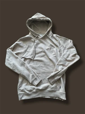 Les deux huvtröja - Snygg beige hoodie med huva och dragsnören. Klassisk känguruficka framtill och ribbade muddar vid ärmar och nederkant. Perfekt för en avslappnad stil och enkel att matcha med jeans eller joggers. Det står M men är lite liten i storlek så skulle ha sagt S.