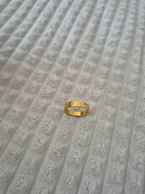 Stainless steel ring  - Snygg stainless steel ring med en liten klar sten och en ingraverad symbol på framsidan. Ringen har en klassisk, rund form och en blank finish som ger ett stilrent intryck. Perfekt accessoar för att lyfta din look.