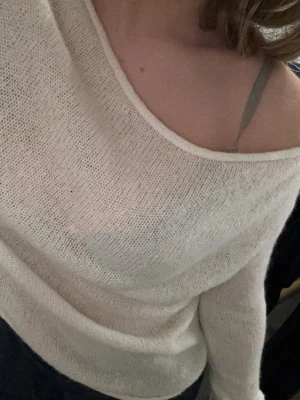 Vit stickad tröja från H&M - Säljer en tunnstickad vit tröja från H&M med bred urringning som kan bäras off-shoulder. Tröjan har lång ärm och är gjord i ett mjukt, lätt material som känns luftigt och skönt. Perfekt för lager på lager och enkel att styla till olika outfits.