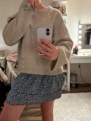 Blommig blå kortkjol med resår - Supersöt kortkjol i mörkblått med små vita blommor och smockad midja. Kjolen har en lätt och flowy känsla, perfekt för varmare dagar. Passar dig som gillar en feminin och avslappnad stil.