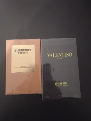Burberry Goddess & Valentino Uomo parfym - Två exklusiva parfymer: Burberry Goddess i en lyxig beige och guldig förpackning, samt Valentino Uomo Born in Roma Yellow Dream i en elegant svart och guldfärgad kartong. Båda flaskorna rymmer 100 ml och har stilren design.