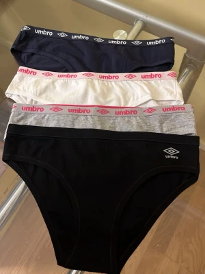 Fyra par trosor från Umbro - Säljer ett 4-pack trosor från Umbro i olika färger: svart, marinblå, vit och grå. Klassisk brief-modell med resår i midjan där Umbro-loggan syns tydligt. Materialet känns mjukt och stretchigt, perfekt för vardagskomfort.