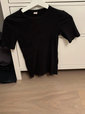 Svart basic t-shirt - En enkel svart t-shirt med rund hals och korta ärmar. Perfekt basplagg i garderoben, lätt att matcha med allt. Tillverkad i mjukt material för skön känsla. Passar dig som gillar minimalistisk och stilren look.