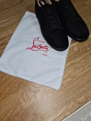 Svarta Christian Louboutin sneakers - Stilrena svarta sneakers från Christian Louboutin med klassisk röd sula och diskret logga. Helt nya storlek 45