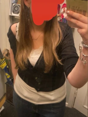 Svart kofta med knappar - Snygg svart kofta med v-ringning och silvriga knappar framtill. Modellen har långa ärmar samt bred mudd nedtill. Perfekt att slänga över ett linne eller t-shirt för en enkel men stilren look. storlek L men sitter som en S. den har några år på nacken men fortfarande mycket att ge.