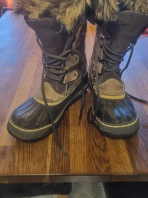 Sorel Joan Of Arctic fodrade vinterstövlar - Sorel's  mest sålda dam stövel.  Inga slitningar på sula eller "fotavtryck" inne i stöveln. Material: " Foten" är i vulkaniserat gummi och 100% vattentät. skaftet i mocka ( suede) likaså. Innerfodret med fuskpäls , är tvättbart (100% återvunnen filt)med milt tvättmedel i kallt/ljummet vatten. skall självtorka. Håller dig garanterat varm!                                  Stl 40, men liten 40. Skulle absolut funka på dig med stl 38,5-39,5.  Innermått fot  25cm     Inköpta för 2499:-