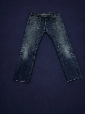 Levi's blå raka jeans herr - Säljer ett par klassiska blå Levi's jeans med raka ben och ett par snygga slitningar på knän och baksida.  Obs vänstra fickan är riven/gått sönder 