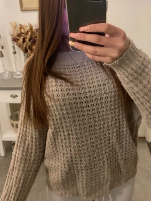 Beige grovstickad tröja - Mysig beige grovstickad tröja med avslappnad passform och rund halsringning. Tröjan har långa ärmar och ett luftigt stickat mönster som ger en trendig och chill vibe. Perfekt att slänga på sig över ett linne eller t-shirt.