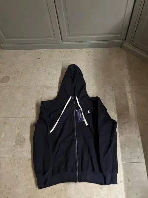 Marinblå polo Ralph lauren zip hoodie  - Säljer en marinblå polo Ralph lauren zip hoodie. Den är i helt ny skick och säljes för ett riktigt bra pris. Storlek S men passar även M😊.                                                 Kom privat vid frågor å funderingar