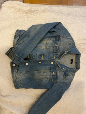 Blå jeansjacka från NLY Jeans - Klassisk blå jeansjacka från NLY Jeans med silverfärgade knappar och flera fickor framtill. Snygga sömmar och tidlös passform som funkar till allt. Perfekt för dig som vill ha en enkel men trendig denimlook.