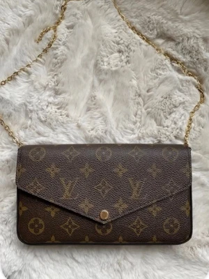 Louis Vuitton monogram kuvertväska - en brun handväska som liknar en lv väska, köpt secondhand och därmed antar jag att den ej är äkta, första bilden är inte min alla andra är. skriv för fler bilder om det behövs. plånboken tillkommer också!