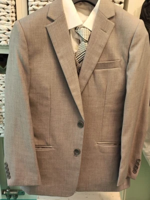 Grå kostym med väst och slips - Stilren grå  kostym med matchande väst och kavaj. Kostymen har klassisk passform, två knappar på kavajen och tre på västen. Medföljer vit skjorta och mönstrad slips. Endast använd 1 gång.