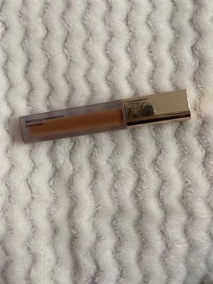 Mattifying Complexion Concealer 15N - Mattifying Complexion Concealer från BeautyAct by KICKS i nyansen No. 15N. Funkar perfekt till bronzer också Kommer i en smidig tub med guldlock och har en varm, mediumbrun ton. Perfekt för att täcka ojämnheter och ge en matt finish. Tillverkad i Italien.