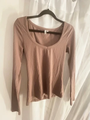 Ribbad tröja - Säljer en ribbad långärmad topp i en mjuk brun/smutslila nyans från Nelly. Toppen är i ett stretchigt material som sitter snyggt på kroppen. Knappt använd. 