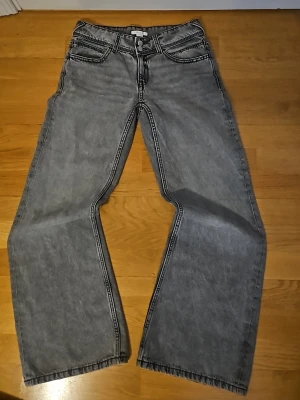 Gråa låg midja vida jeans - Säljer ett par gråa låg midja vida jeans. Jeansen har jätte fin fick design. Jeansen är helt nya. Storlek W24, 32, eller Xs. Pris kan diskuteras 🫶