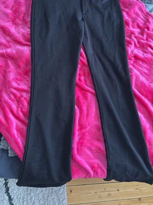 Svarta kostymbyxor från 157 - Säljer ett par svarta kostymbyxor från 157 med raka ben och klassisk passform. Byxorna har diskreta hyskor i midjan och är tillverkade i ett mjukt tyg som känns bekvämt. Perfekta för en clean och stilren look. Säljer pågrund av de är för stora och kommer inte till användning! Byxorna är helt nya och har endast provats en gång!