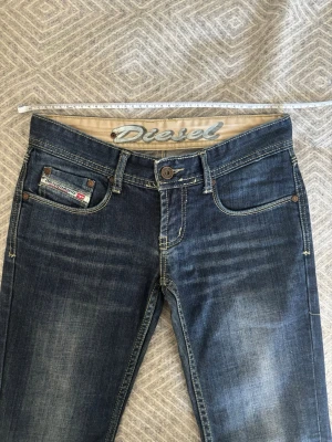 Blå lågmidjade jeans från Diesel  - Snygga blå jeans från Diesel. De är i nyskick och alla mått står på bilderna! Hör av dig vi frågor ex mått på hur lågmidjade de är💕