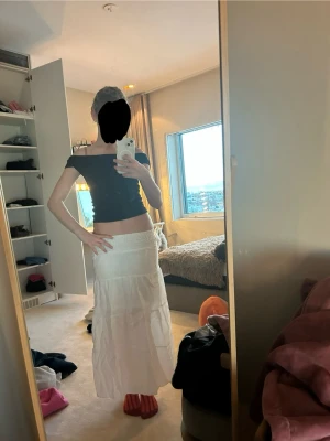 Vit långkjol med volangdetaljer - Säljer en vit långkjol med bred resår i midjan och flera volangdetaljer. Sitter alldeles för tajt och är alldeles för kort för mig så ursäktar det