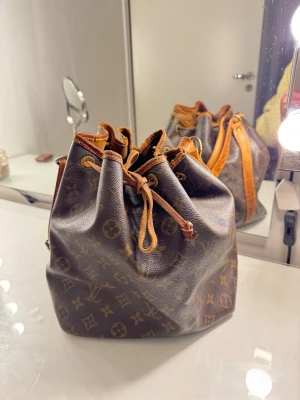 Louis Vuitton Monogram Noé handväska -  Louis Vuitton Noé handväska med dragskostängning och justerbar axelrem. Så fin och användbar!