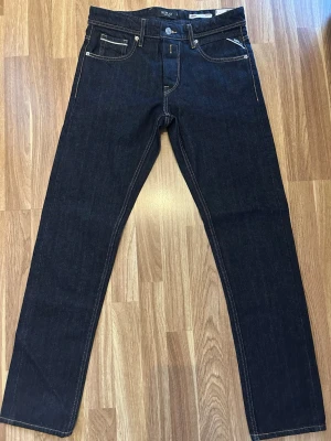 Helt nya Mörkblå replay Jeans - Säljer ett par mörkblå jeans från replay  med klassisk femficksmodell och raka ben. Jeansen har kontrastsömmar och är tillverkade i kraftig denim. Perfekta för dig som gillar en stilren och tidlös look.