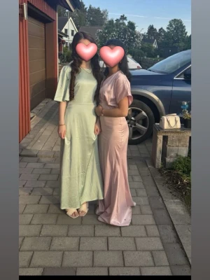 Ljusrosa långklänning med v-ringning - Elegant ljusrosa långklänning med v-ringad hals och korta ärmar. Klänningen har en figurnära passform och är tillverkad i ett glansigt silkes material som ger en lyxig känsla. Perfekt för speciella tillfällen och studentfirande. Pris kan diskuteras!❤️