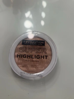 Revolution Super Highlight highlighter - Säljer en Revolution Super Highlight highlighter i en rund dosa med genomskinligt lock. Färgen är en varm, skimrande champagneguld med en pressad, vågig yta. Ger ett superglow och har en mjuk, lättblendad textur som verkligen poppar på huden.