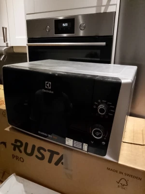 Mikrovågsugn från Electrolux - Säljer en svart och silver mikrovågsugn från Electrolux med roterande grillfunktion. Fronten har en stor glaslucka och två vred för inställningar. Snygg och enkel design i metall och plast, perfekt för köket.